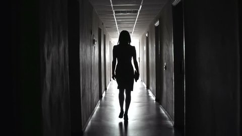 Camera following business-like unrecognizable lady tripping along dark hallway