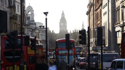 LONDON, CIRCA MARCH 2014 - Red London buses and traffic drive on a street with Big Ben in the background. Dolly/tracking movement