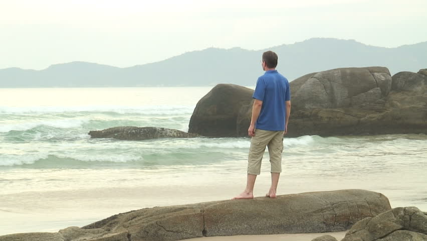 HD 1080i: Man standing on a rock and looking at the sea.