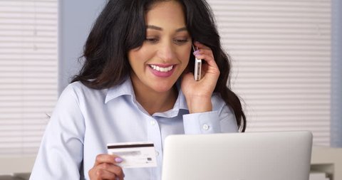 Hispanic woman making a purchase over the phone