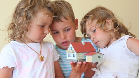 two little girls and boy with toy house indoor 