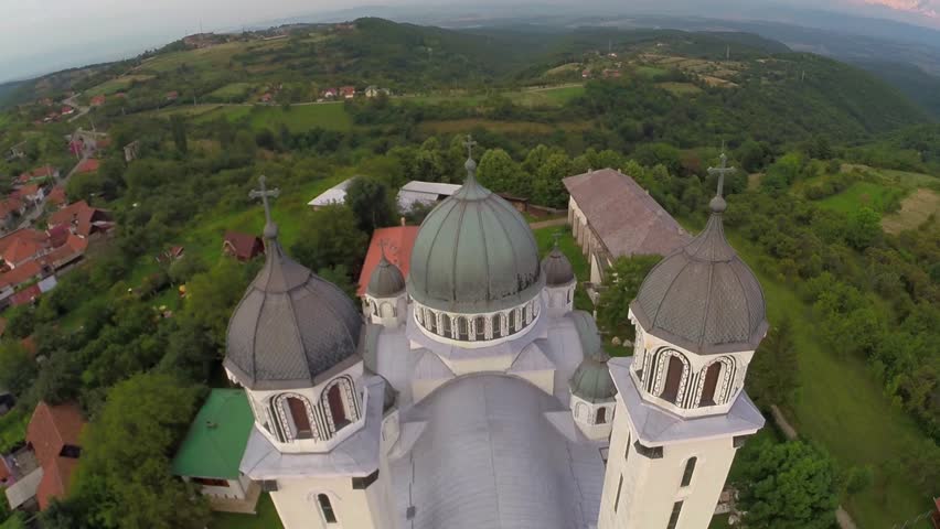 Aerial view over cathedral on countryside in mountains at sunset