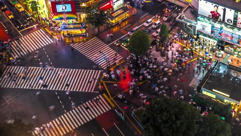 TOKYO, JAPAN - MAY 16, 2013: Time lapse video of people with umbrellas cross the famous diagonal intersection in Shibuya, Tokyo, Japan.