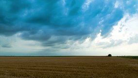 Time-lapse video of vibrant stormy clouds over stubble agricultural field