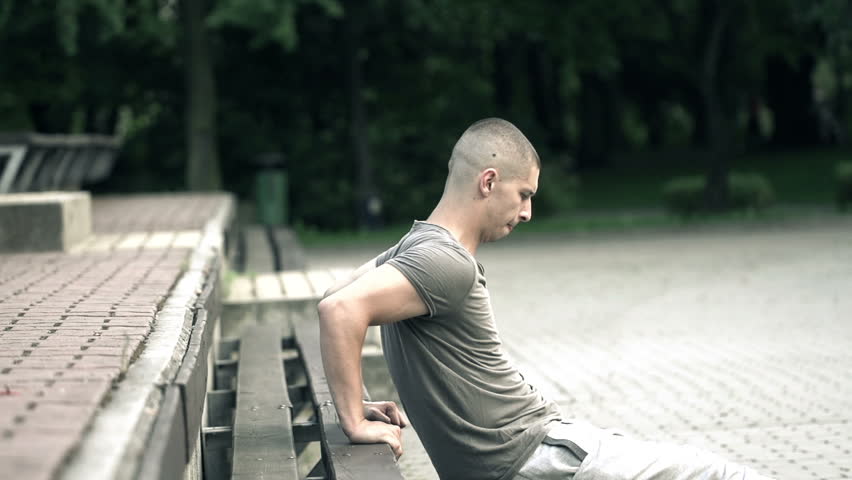 Two man exercising, doing push-ups in city park

