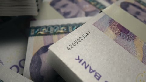 An extreme closeup pan across variously placed bundled wads of  Norwegian Krone banknotes