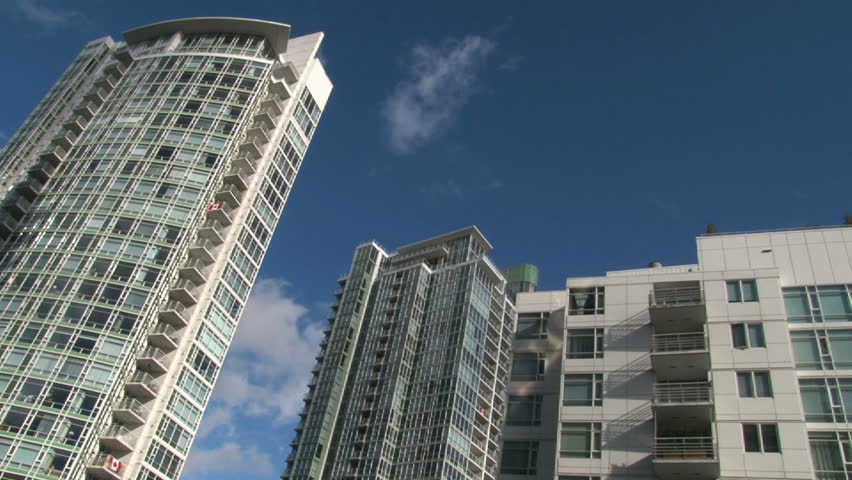 Seagull flies across frame of tall condominiums in Vancouver Canada during