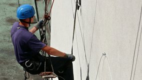 Worker climber; Specially equipped worker performs working in the hights on skyscraper,video clip