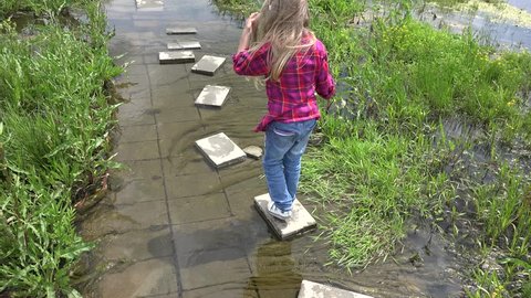 Ultra HD 4K View of a Child Playing in Puddle after a Rainy Day, Little Girl Jumping in Water