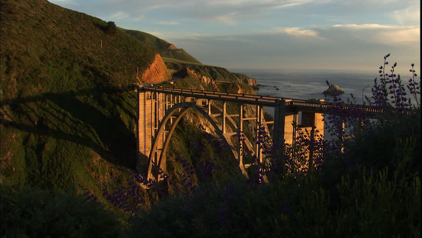 Wide shot of a bridge crossing the ocean in Big Sur at sunset