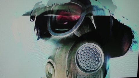 a person wearing a gas mask. this footage has been passed through an analogue video effects unit to add an interesting and unique distortion and static look

