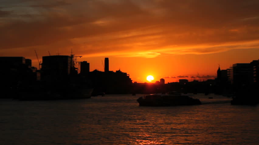 A tourist vessel sails through the Thames River with London skyline in the background.
