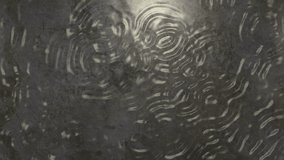 Rain drops falling in puddle, storm ends and sun is reflected. Loops: first 5 seconds and last 8 seconds. Weather background animation.  In 4K ultra HD and smaller sizes.