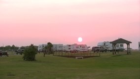Video of a recreation vehicle campground at sunset. South Texas on Corpus Christi Navy Station. Several travel trailers and RV vehicles. Grass park. 