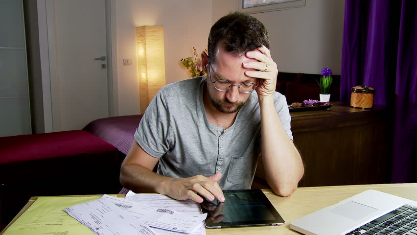 Man at home calculating bills and taxes with tablet calculator