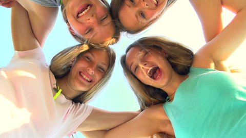 Group of Four Teenage Girls having fun outdoors. Friendship concept. Group of smiling friends staying together, looking at camera and laughing over blue sky. Joyful girlfriends. Slow motion 1080