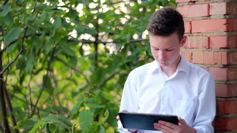 Young Male Student With Tablet Computer In The Park
