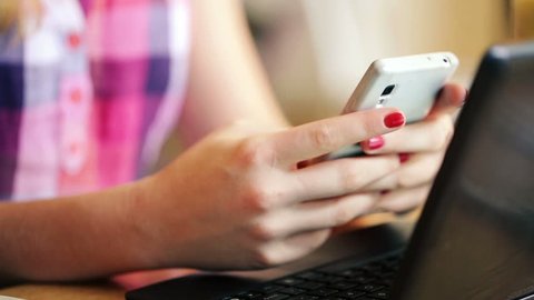 Girl hands sending sms on smartphone in cafe
