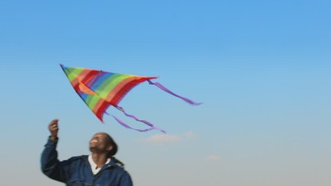 Steadicam shot of African American man running and flying kite. 