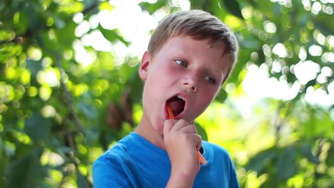 Nearly 7 years young boy is brushing his teeth in green background
