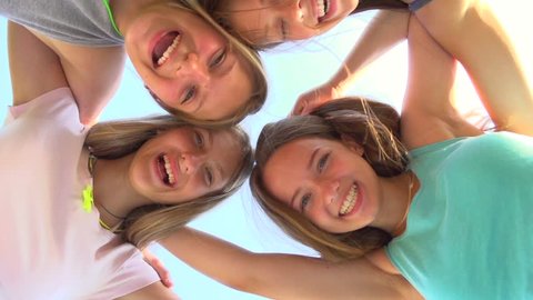 Group of Four Teenage Girls having fun outdoors. Friendship concept. Group of smiling friends staying together, looking at camera and laughing over blue sky. Joyful girlfriends. Slow motion 1080p