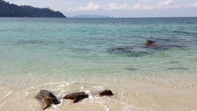View of white sand, big rock, beach, blue sky with clouds and harmony waves at Lalang Island, Lumut, Perak, Malaysia, facing to Straits of Malacca