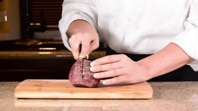 Chef Chopping Red beet in half on wooden cutting board
