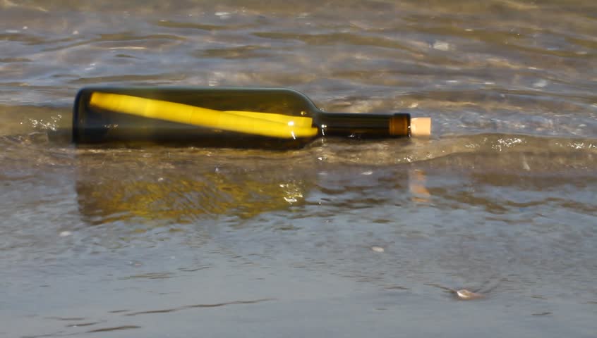 secret message in a bottle on the sandy sea shore with waves