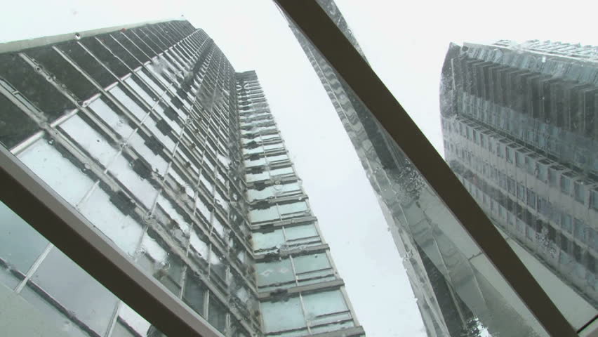 Low angle shot looking up at tall buildings during rain storm.