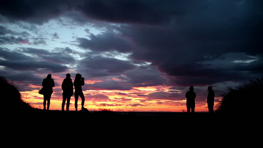 Silhouettes of women and men watching a dramatic sunset on an Icelandic beach near Reykjavik | Shutterstock HD Video #7045216