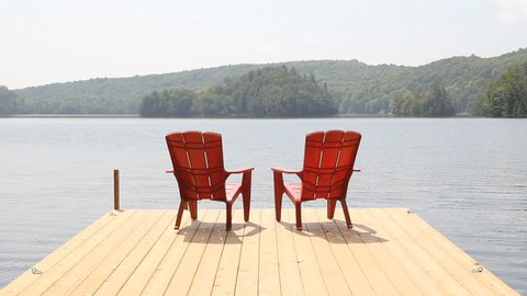 Two red chairs on cottage dock. Sunny morning. Medium shot.
Two red chairs on a floating wooden dock. Sunny morning in Haliburton county, Ontario, Canada. Medium shot.
