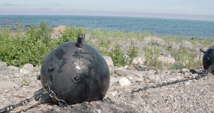 A big black sea mine on top of a hill near the sea. Under the scorching heat of the sun the sea mine along with the others are found on the rocky ground with the view of the  sea FS700 Odyssey 7Q 4K