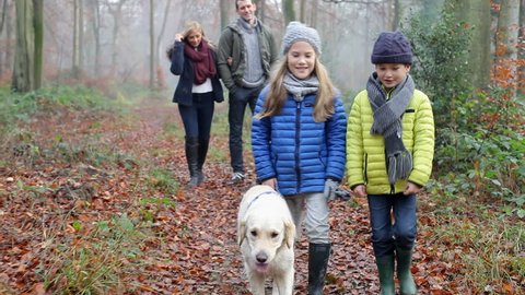 Family Walking Dog Through Winter Woodland
