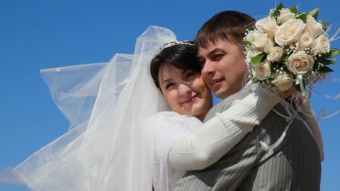 bridegroom and bride kissing outdoor, blue sky in background 