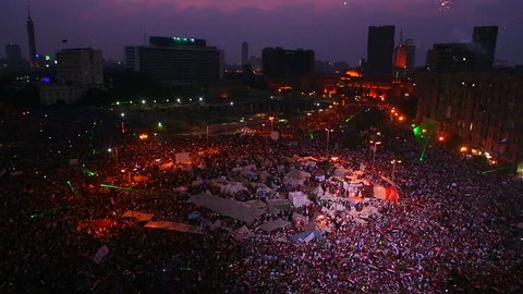 Fireworks go off above protestors gathered in Tahrir Square in Cairo, Egypt at a large nighttime rally.