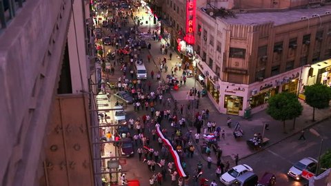 Overhead view looking at an intersection as protestors march in the streets of Cairo, Egypt at night.