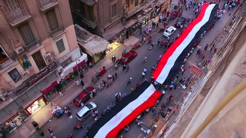 View from overhead looking straight down as protestors carrying banners march in the streets of Cairo, Egypt.