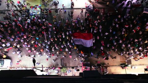View from overhead looking straight down on protestors marching in the streets of Cairo, Egypt at night.