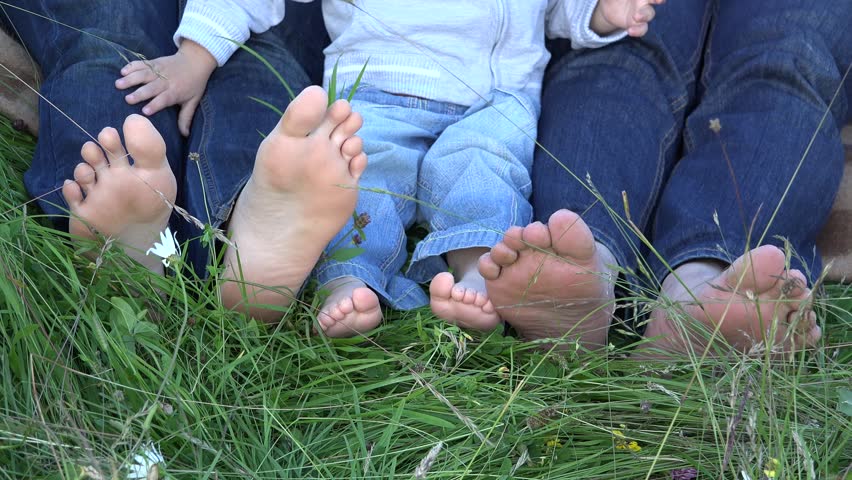 Family feet. Parents and children on the grass. Barefoot Family. Barefoot mother.