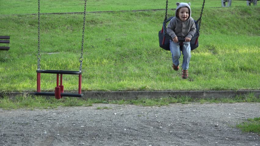 Little boy enjoying to balance in rocking chair near a empty chair