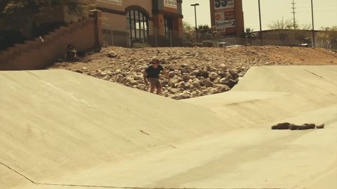 A skateboarder skateboarding in a skatepark, uses his hand to change skateboard's direction