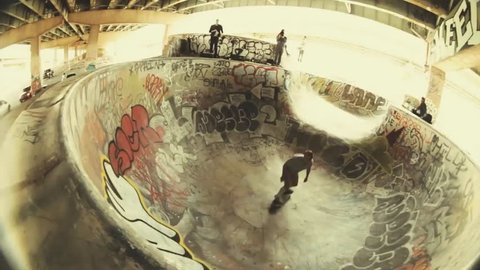 A skateboarder showing lip tricks while skateboarding in a halfpipe, top angle