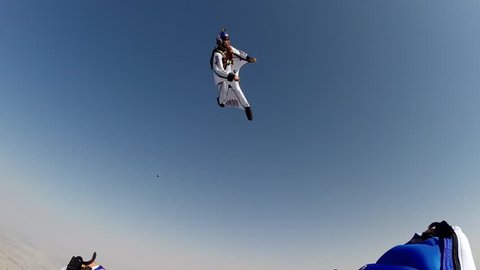 A skydiver in a wingsuit skydiving in the sky with Dubai cityscape visible below, POV