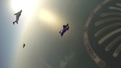 Skydivers in wingsuits skydiving in the sky with Dubai cityscape visible below, POV