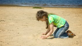 Video 1080p - Little girl playing with sand on the shore of a large river