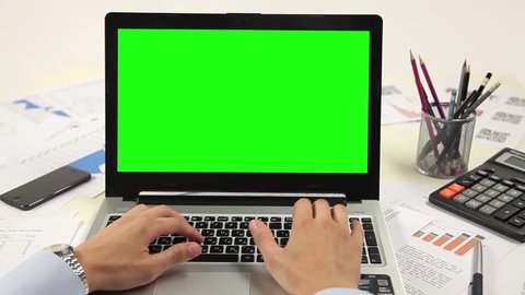 Man hand on laptop keyboard with green screen monitor in the office