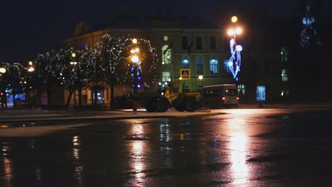 SAINT PETERSBURG, RUSSIA - JANUARY 04, 2014: Orange snow-plough working at night street decorated with Christmas lights.