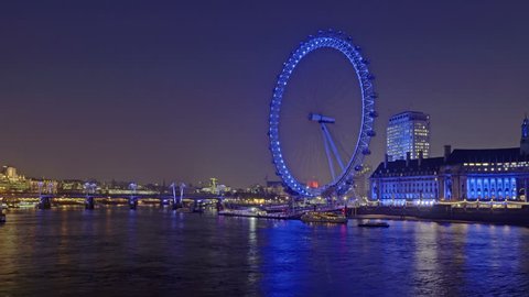 Panning, time-lapse of the London Eye from across the river Thames at night.