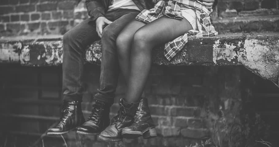 Guy and girl sitting on ledge with boots dangling from it