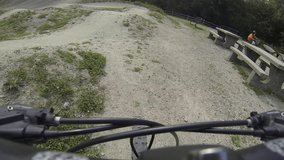 1080p wide angle video of a mountain biker riding over rolling bumps at the bike skills park on a sunny day. Shot with a handlebar mounted action camera at 60fps, perfect for slow motion edits.